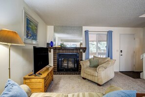 Ein Wohnzimmer mit Kamin, Fernseher, Holzschrank und einer Couch.