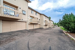 A residential building with multiple garage doors, a paved driveway, and a clear sky. - The Broadmoor Condo | 2 Queens + Garage (Colorado Springs)