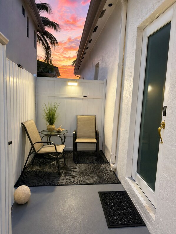 A covered patio area with two chairs, a small table, and a potted plant. - Private Miami Suite (Miami)