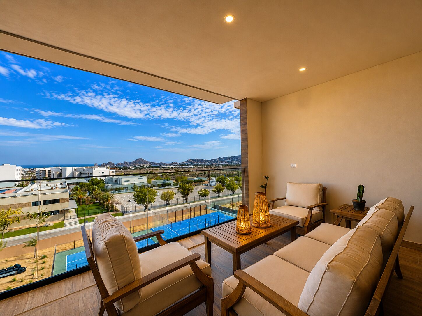 A balcony with a view of a tennis court, a pool, and distant buildings.