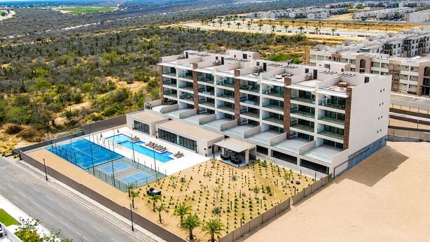 Ein modernes Mehrstöckhotel mit Pool auf dem Dach und einem begrünten Innenhof.