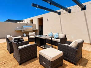 An outdoor patio with wicker furniture, a grill, and string lights. - CASA CIAN • LUXURY PENTHOUSE SUITE • OCEAN & ARCH VIEWS • PRIVATE ROOFTOP (Cabo San Lucas)