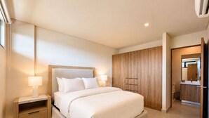 Ein modernes Schlafzimmer mit einem großen Bett, Nachttischen, einem Kleiderschrank und einem durch eine offene Tür einsehbaren Badezimmer.
