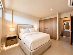 A modern bedroom with a large bed, bedside tables, a wardrobe, and a bathroom visible through an open door. - CASA CIAN • LUXURY PENTHOUSE SUITE • OCEAN & ARCH VIEWS • PRIVATE ROOFTOP (Cabo San Lucas)