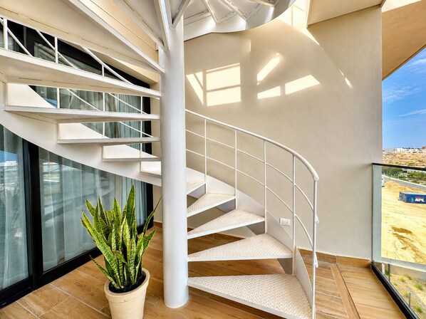 Et moderne interiør med en spiraltrappe, store vinduer og en potteplante.