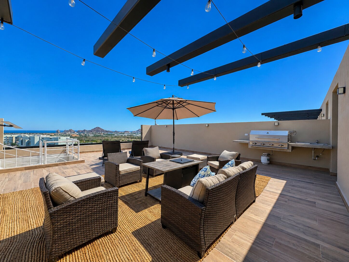 An outdoor patio with wicker furniture, a grill, and string lights.