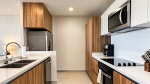 Eine moderne Küche mit Holzausstattung, Edelstahlgeräten und einer schwarzen Kaffeemaschine.