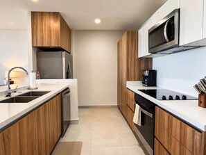 A modern kitchen with wooden cabinets, stainless steel appliances, and a black coffee maker. - CASA CIAN • LUXURY PENTHOUSE SUITE • OCEAN & ARCH VIEWS • PRIVATE ROOFTOP (Cabo San Lucas)