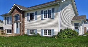 A two-story house with a brick chimney, multiple windows with shutters, and a well-maintained lawn.