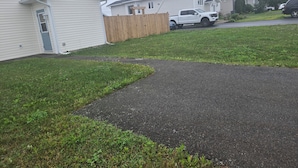 A residential driveway with a wooden fence, a white pickup truck, and houses in the background. - Bright & Cozy One Bedroom Getaway (Grand Falls-Windsor)