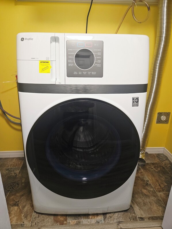 A front-loading white washing machine with a control panel, a yellow caution label, and a 10-year limited warranty badge.