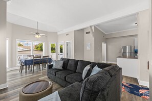 A modern living room with a sectional sofa, dining area, and kitchen. - Walk to the Beach | 5 Minutes to St. Andrews State Park | Easy Access | Updated (Panama City)