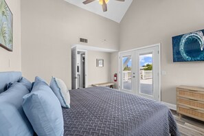 Une chambre à coucher comprenant un lit, un ventilateur de plafond, une porte donnant sur un balcon et un extincteur.
