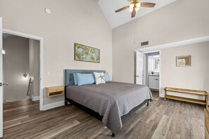 A bedroom with a bed, a ceiling fan, a wall-mounted light, and a door leading to another room. - Walk to the Beach | 5 Minutes to St. Andrews State Park | Easy Access | Updated (Panama City)