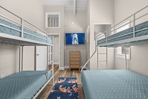 A dormitory room with bunk beds, a television, a wardrobe, and a patterned rug. - Walk to the Beach | 5 Minutes to St. Andrews State Park | Easy Access | Updated (Panama City)