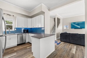 A modern kitchen with white cabinets, a blue backsplash, and a stainless steel refrigerator. - Walk to the Beach | 5 Minutes to St. Andrews State Park | Easy Access | Updated (Panama City)
