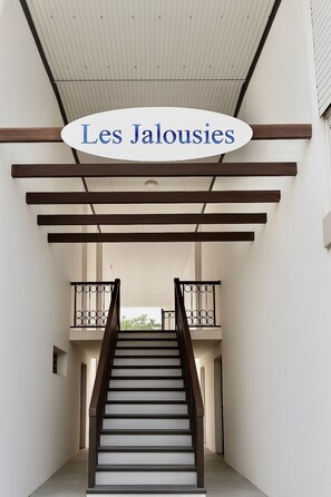A staircase with a wooden handrail and a white ceiling. - Lovely & Cozy 1-Bedroom Loft with AC & Tropical Patio, 5 Minutes from Marigot (Marigot)