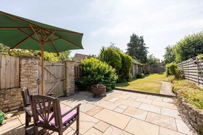 A patio area with a wooden table, chairs, and a green umbrella.