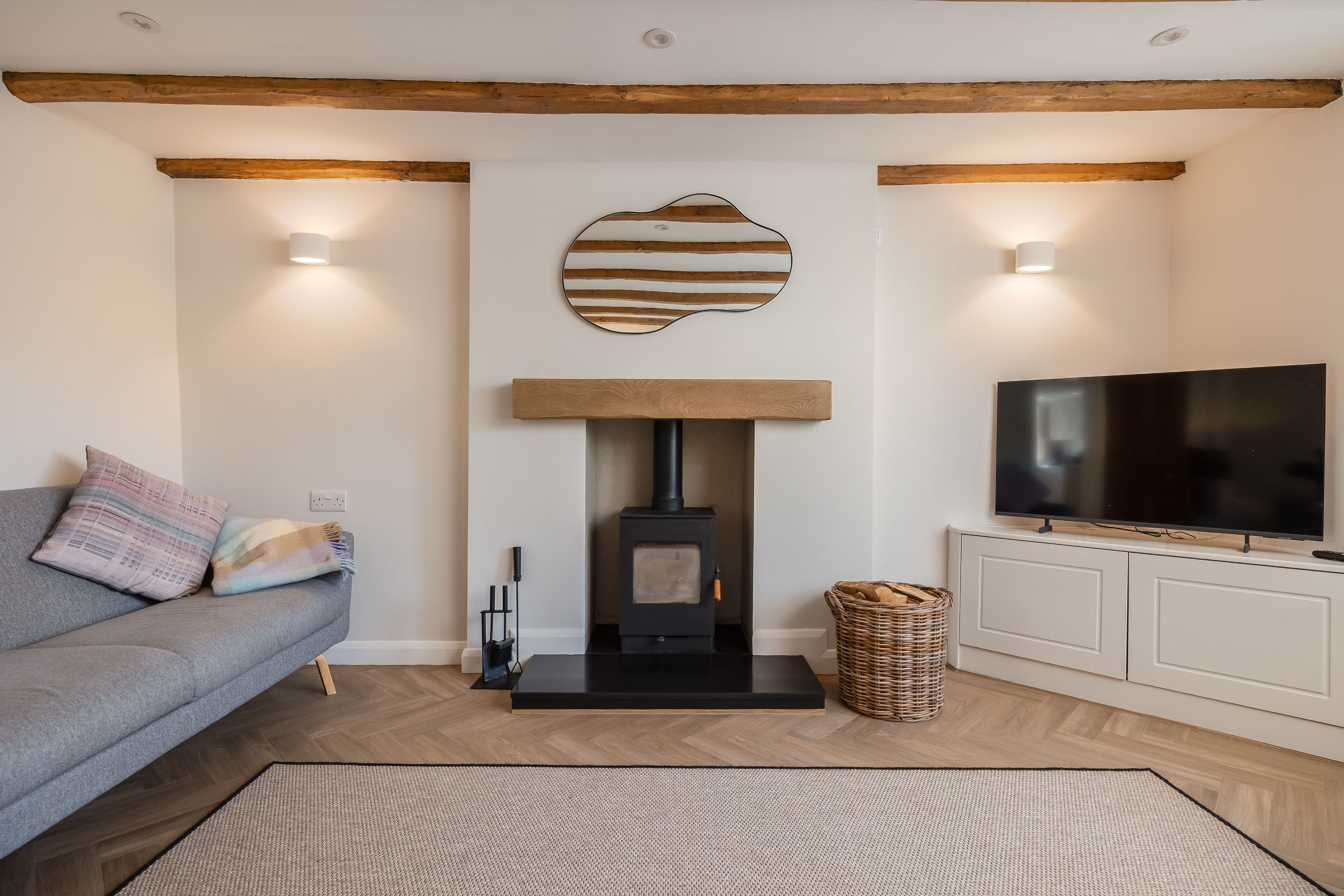 A living room with a sofa, a fireplace, a television, and a woven basket.