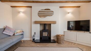 A living room with a sofa, a fireplace, a television, and a woven basket.
