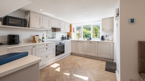 Una cocina moderna con armarios blancos, horno integrado y un amplio ventanal con vistas al exterior.