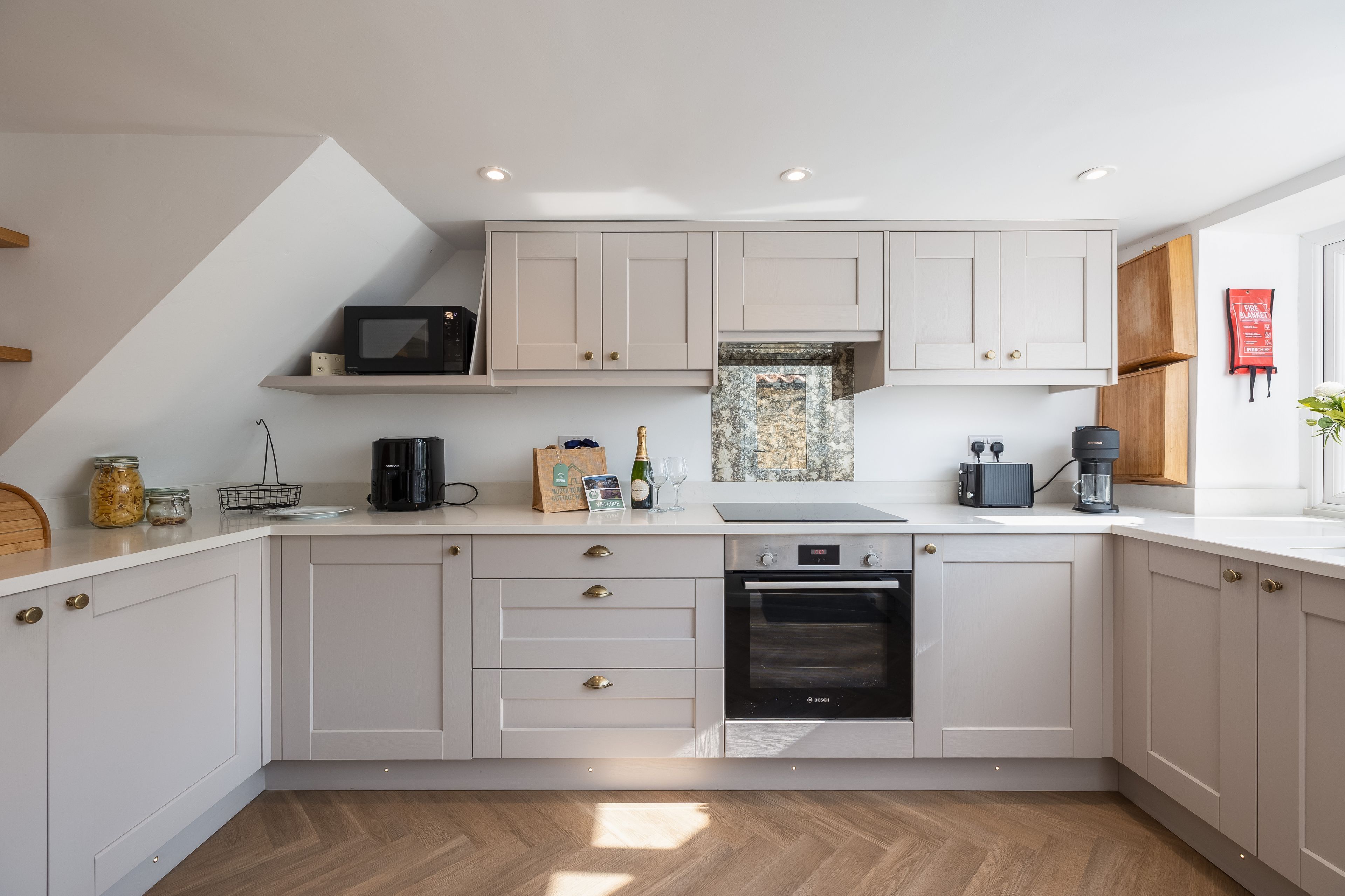 A modern kitchen with white cabinetry, a Bosch oven, and a coffee machine.