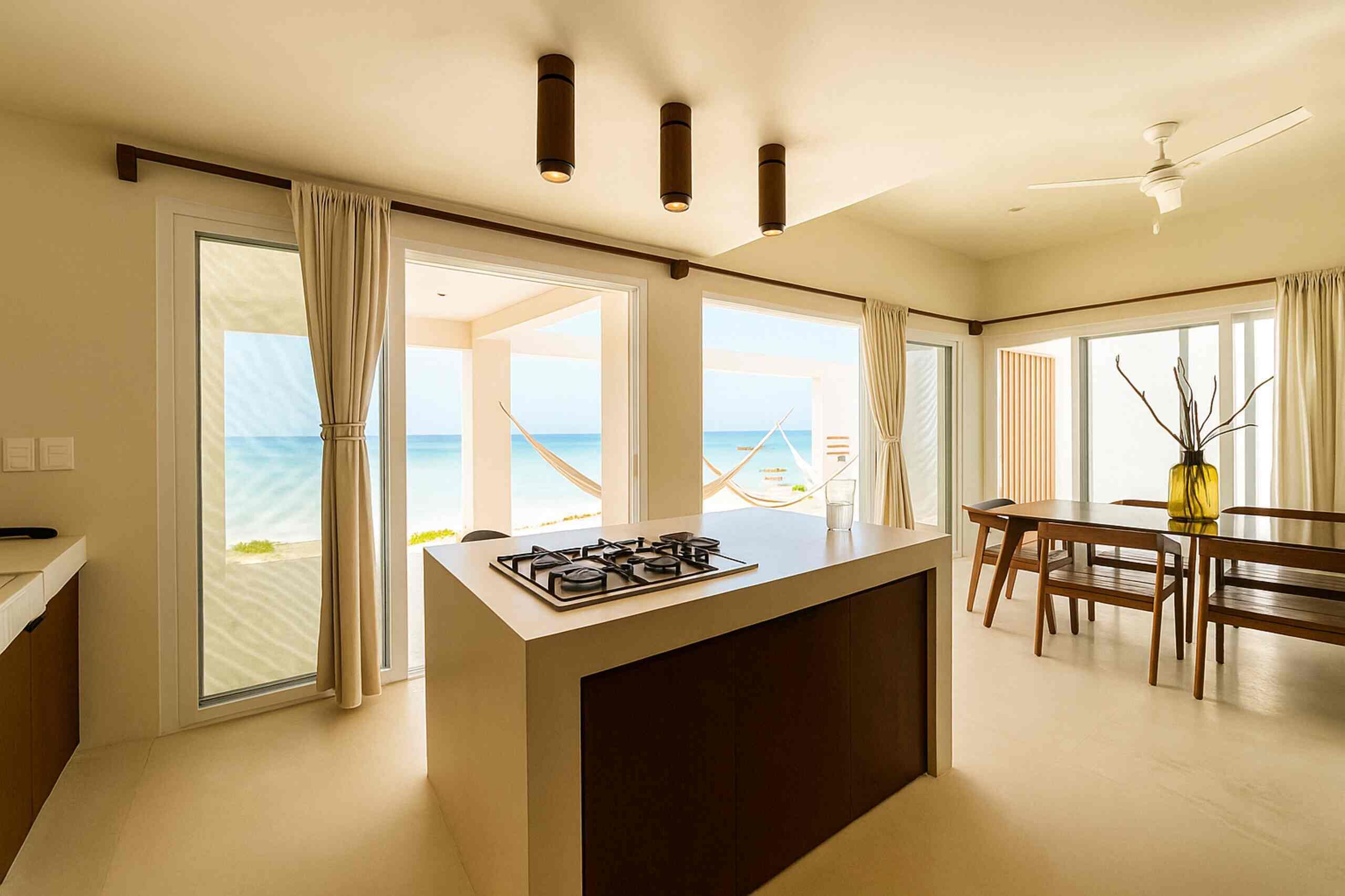 A modern kitchen with a central island, large windows, and a view of the beach.