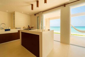 A modern kitchen with a central island, a large window, and a view of the beach. - Beachfront house with a pool, 15 minutes from Progreso (Chuburna Puerto)