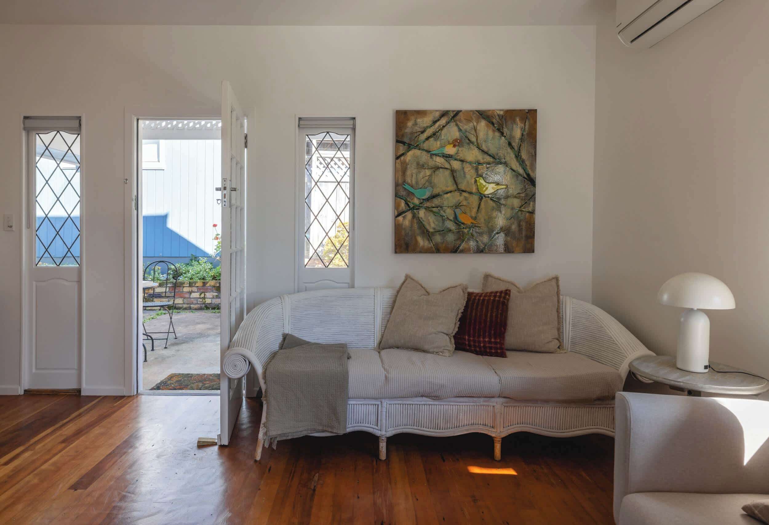 A room with a white sofa, a painting, and a lamp.