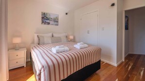 Un dormitorio con cama, mesitas de noche, un cuadro y un armario.