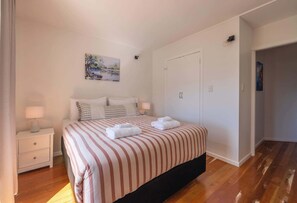 Ein Schlafzimmer mit einem Bett, Nachttischen, einem Gemälde und einem Kleiderschrank.