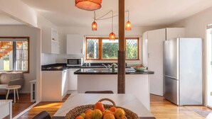 Cocina moderna con una isla central, refrigerador e iluminación colgante.