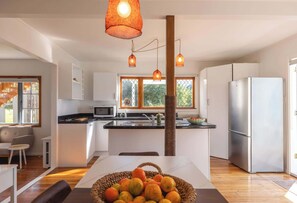 Eine moderne Küche mit Kochinsel, Kühlschrank und Pendelleuchten.