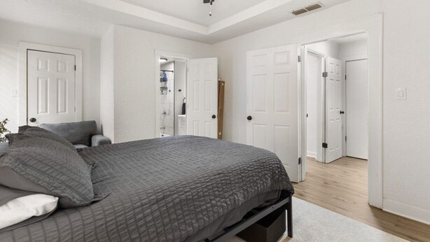 A bedroom with a bed, a ceiling fan, and white doors leading to other rooms. - The Lucile - Spacious 4BR Extended-Stay Home | Fast Wi-Fi & Parking (Wichita Falls)