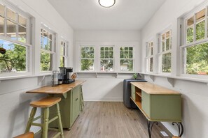 A compact kitchen with a wooden countertop, stools, and green cabinets. - The Lucile - Spacious 4BR Extended-Stay Home | Fast Wi-Fi & Parking (Wichita Falls)