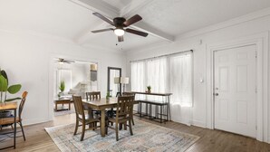 A spacious dining area with a wooden table and chairs, a ceiling fan, and a patterned rug. - The Lucile - Spacious 4BR Extended-Stay Home | Fast Wi-Fi & Parking (Wichita Falls)