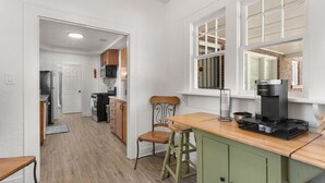 A compact kitchen with a coffee maker, wooden cabinets, and a window with a view. - The Lucile - Spacious 4BR Extended-Stay Home | Fast Wi-Fi & Parking (Wichita Falls)