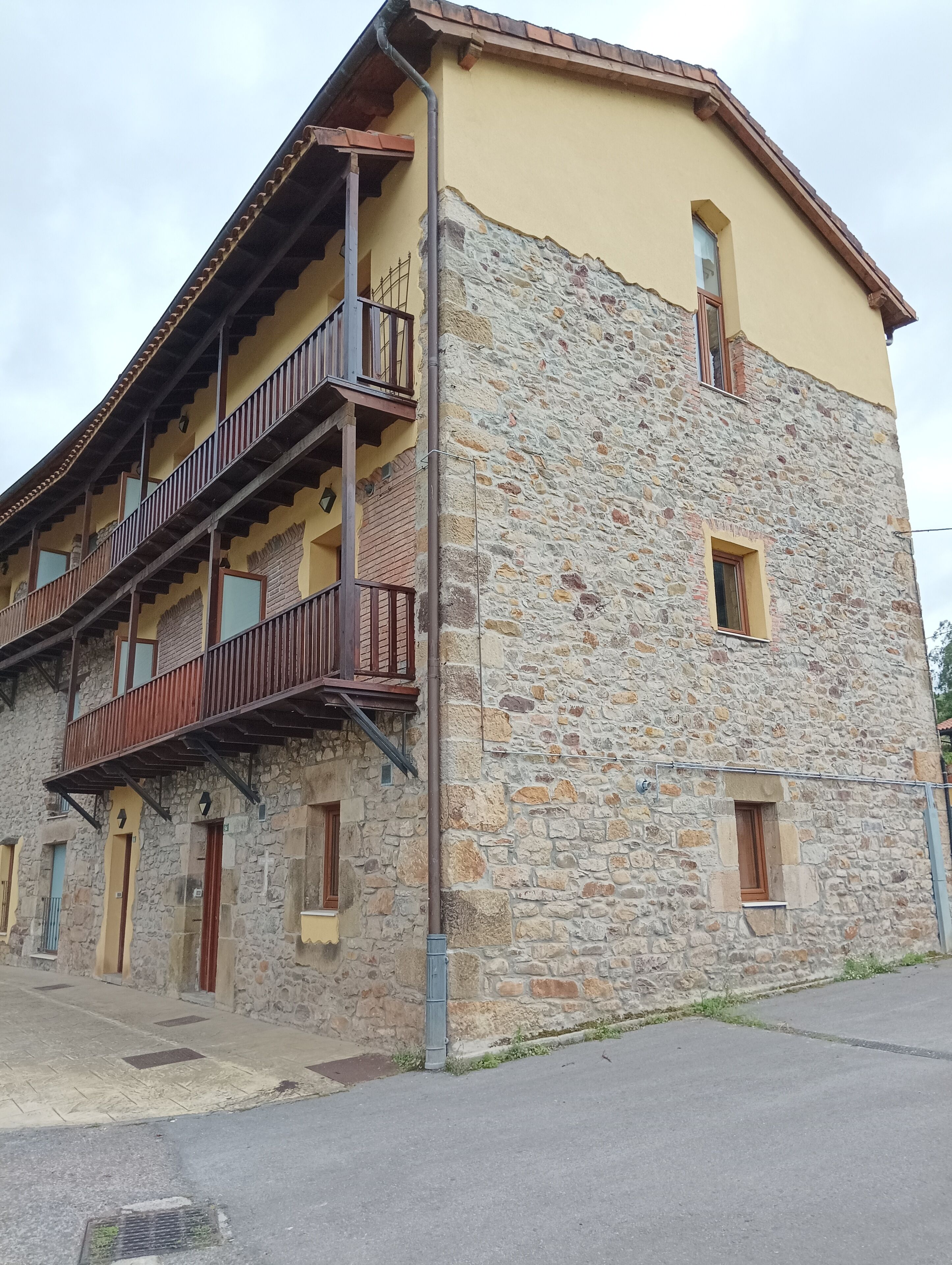 A two-story building with a stone facade and a balcony on the upper floor.