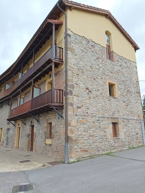 Ein zweigeschossiges Gebäude mit einer Steinfassade und einem Balkon im oberen Stockwerk.