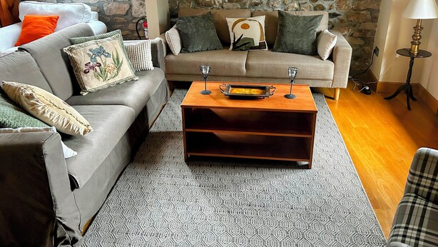 A living room with two sofas, a coffee table, and a stone wall. - Superb 3-bedroom townhome in charming Liérganes awaits you (Liérganes)