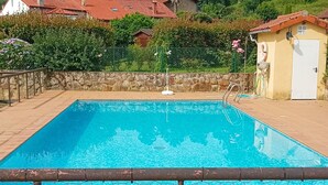 A rectangular swimming pool with a tiled deck, surrounded by a stone wall and a metal fence. - Superb 3-bedroom townhome in charming Liérganes awaits you (Liérganes)