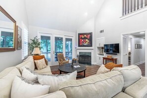 A living room with a fireplace, a television, and a large window.