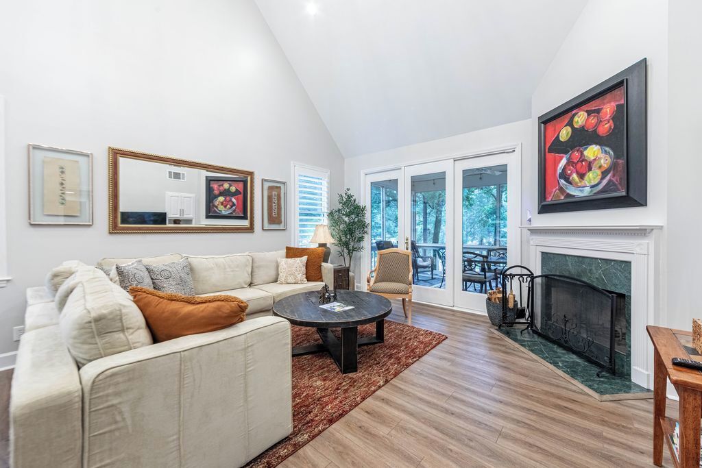 A living room with a sofa, coffee table, fireplace, and artwork on the walls.