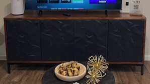 Un téléviseur affichant l’interface d’un service de diffusion en continu, avec différentes options, une télécommande et un bol décoratif posé sur une table.
