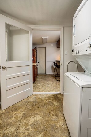 A laundry room with a washing machine, a dryer, and a door leading to a kitchen area with a dining table and chairs. - Newly renovated 3/2 in the middle of town (Jonesboro)
