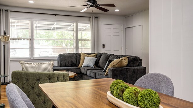 Ein modernes Wohnzimmer mit einem dunkelgrauen Ecksofa, einem grünen Sessel und einem Holzessttisch.