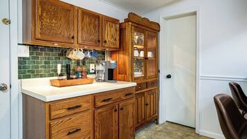 A kitchen with wooden cabinets, a coffee maker, and a tiled backsplash.
