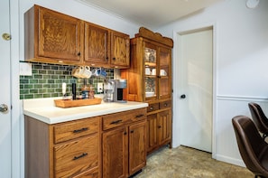 A kitchen with wooden cabinets, a coffee maker, and a tiled backsplash.