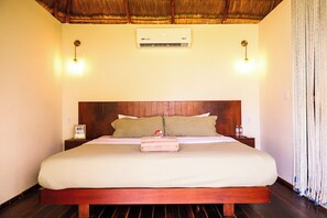 Habitación de hotel con cama de madera, aire acondicionado en la pared y un cartel que indica disponibilidad de WiFi.