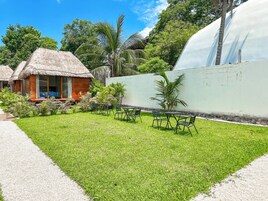 A well-maintained lawn with outdoor seating and a thatched-roof structure.